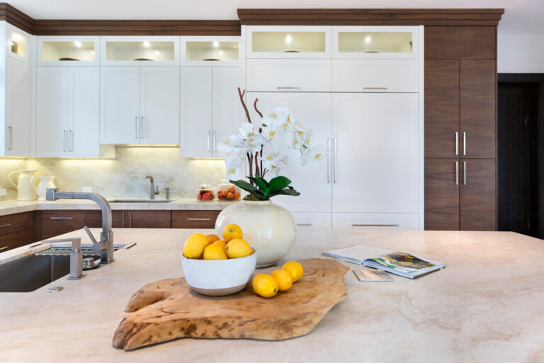 Home-staged modern kitchen with white and wood cabinetry, a large island, fresh lemons, and white orchids as decorative accents.